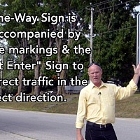The One-Way Sign is often accompanied by white lane markings and the "Do Not Enter" Sign.