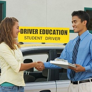 A driving instructor congratulates his student on passing her road test first time.