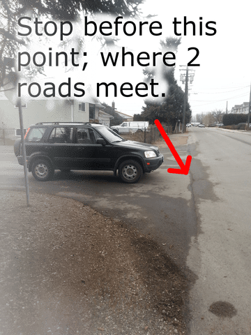 If there isn't a STOP line, sidewalk or crosswalk lines, then stop at the edge where the two roads meet. Often there is a slight line in the bitumen.